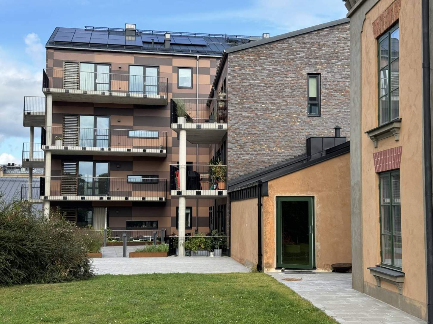 Gården har fasader i Swiss Pearl Terra. Kulörer avstämt mot tegelfasaderna och befintligt byggnad.